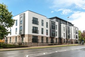 Modern newly built housing block with brown brick and cream rendered walls and dark grey window frames and railings