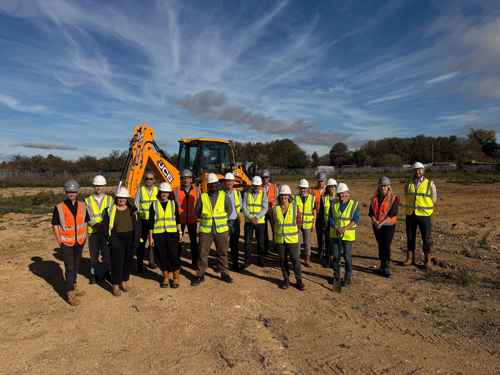 picture of people from Bromford, Cheltenham Borough Council and Homes England in hard hats and high vis jackets. They are all standing in front of a digger on a building site